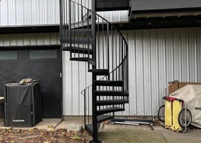 Simple iron spiral staircase connects the back deck to the ground level in a Portland, Oregon residential back yard